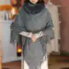 Poncho en maille gris avec capuche fourrée et franges.