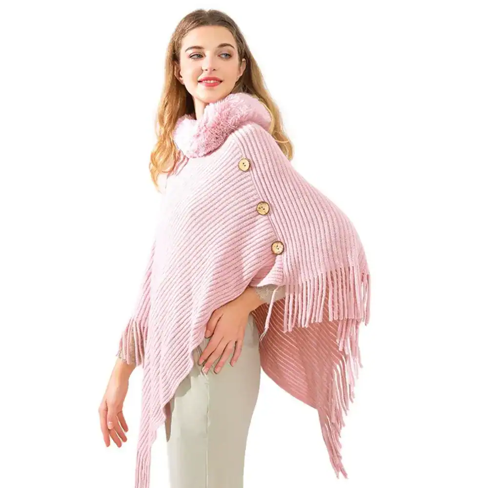 Poncho en maille rose avec franges et capuche en fourrure synthétique.