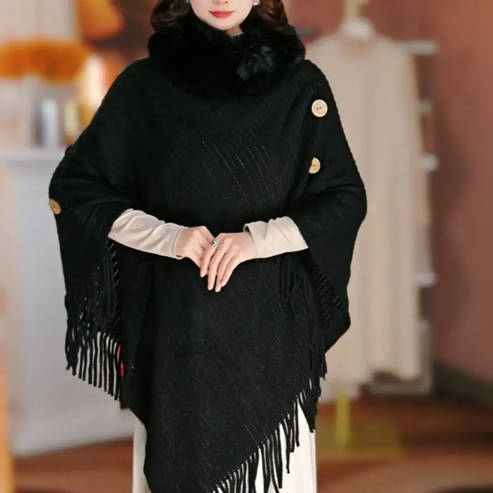 Poncho noir à franges et capuche fourrée, boutons dorés, style élégant.