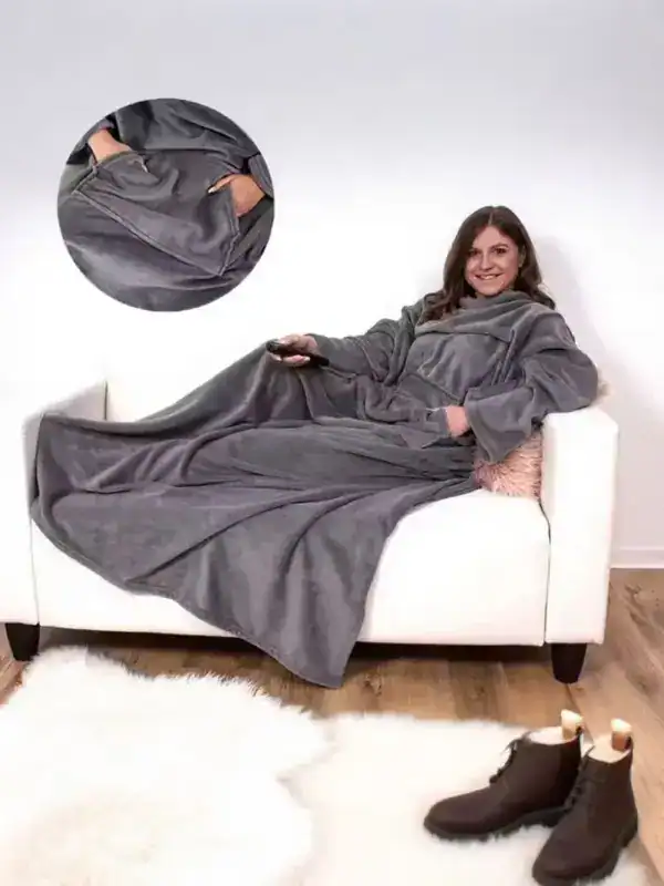 Poncho couverture polaire gris, capuche, poches, confortable sur canapé.