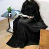 Poncho couverture polaire noir avec capuche, idéal pour lire confortablement sur un canapé.