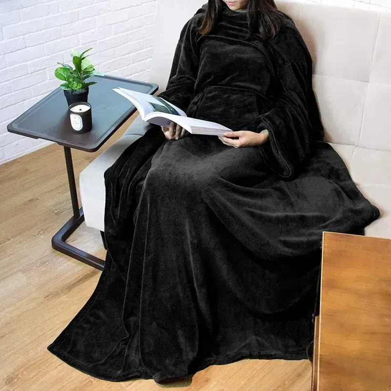 Poncho couverture polaire noir avec capuche, idéal pour lire confortablement sur un canapé.