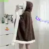 Poncho pilou pilou marron à motif torsade avec doublure blanche et capuche.