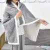Poncho plaid gris femme avec bordure blanche douce et capuche intégrée.