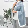 Poncho plaid femme bleu clair avec capuche et bordure blanche.