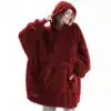 Poncho plaid polaire rouge, capuche, poches avant, look confortable.