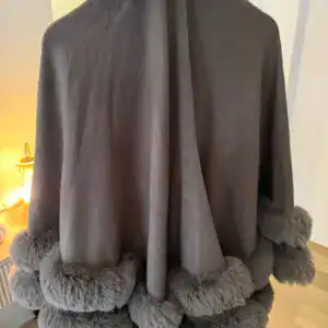 Poncho cape taupe bordé de pompons effet fourrure