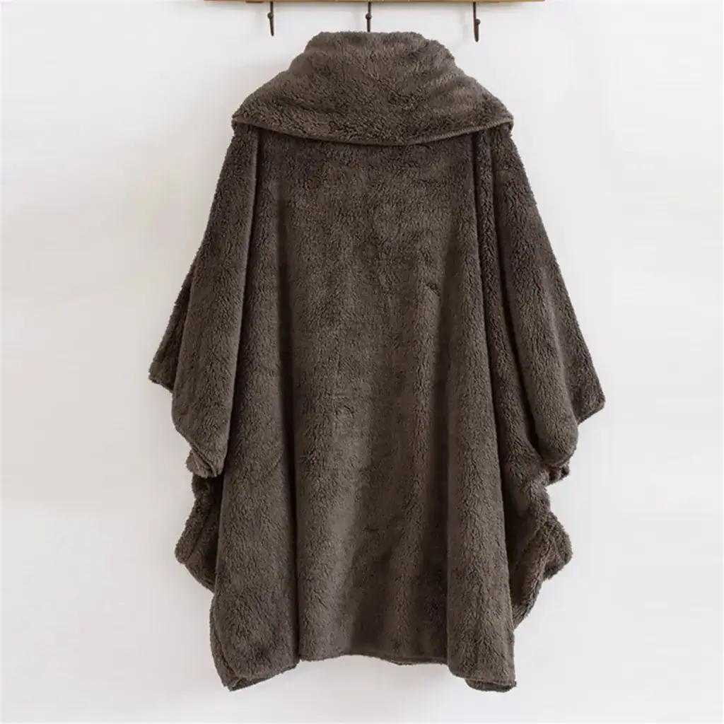 Poncho plaid sans capuche en tissu doux marron, suspendu à un cintre.