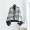 Poncho polaire à carreaux gris et blanc avec capuche doublée et boutons.