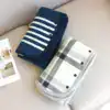 Poncho polaire avec boutons, motif rayures bleues et carreaux gris, plié sur canapé.