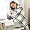 Poncho polaire à carreaux gris et blanc, avec capuche et boutons, pour lecture confortable.