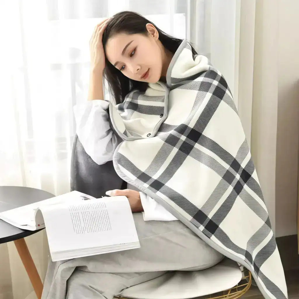 Poncho polaire à carreaux gris et blanc, avec capuche et boutons, pour lecture confortable.